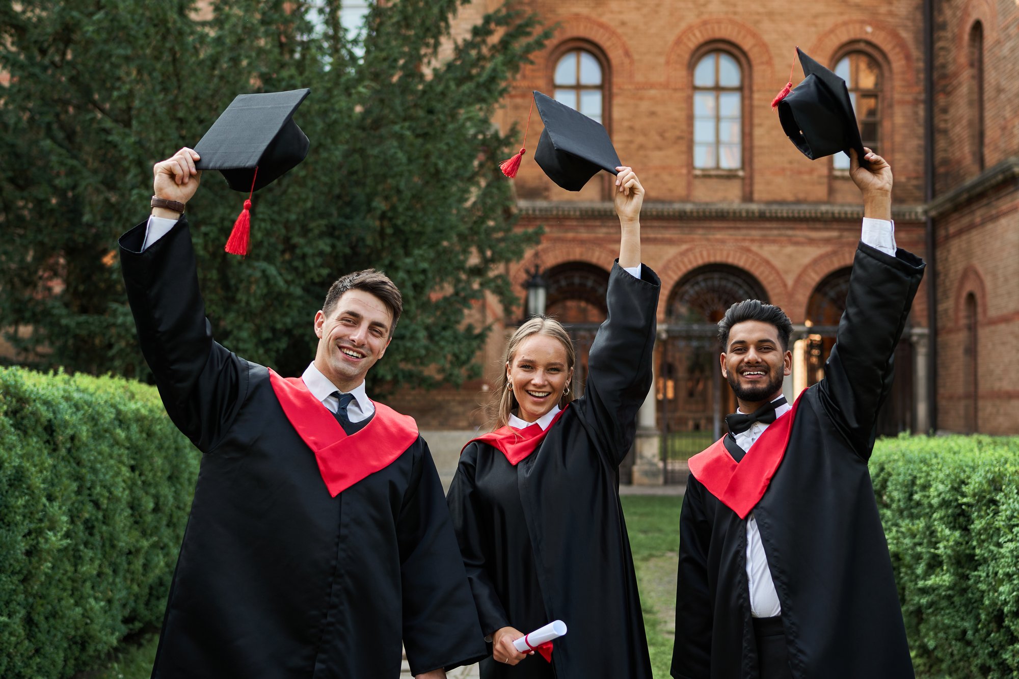 multinational-graduates-male-female-celebrating-graduation-university-campus-removing-their-graduation-hats-smiling-camera multinational-graduates-male-female-celebrating-graduation-university-campus-removing-their-graduation-hats-smiling-camera